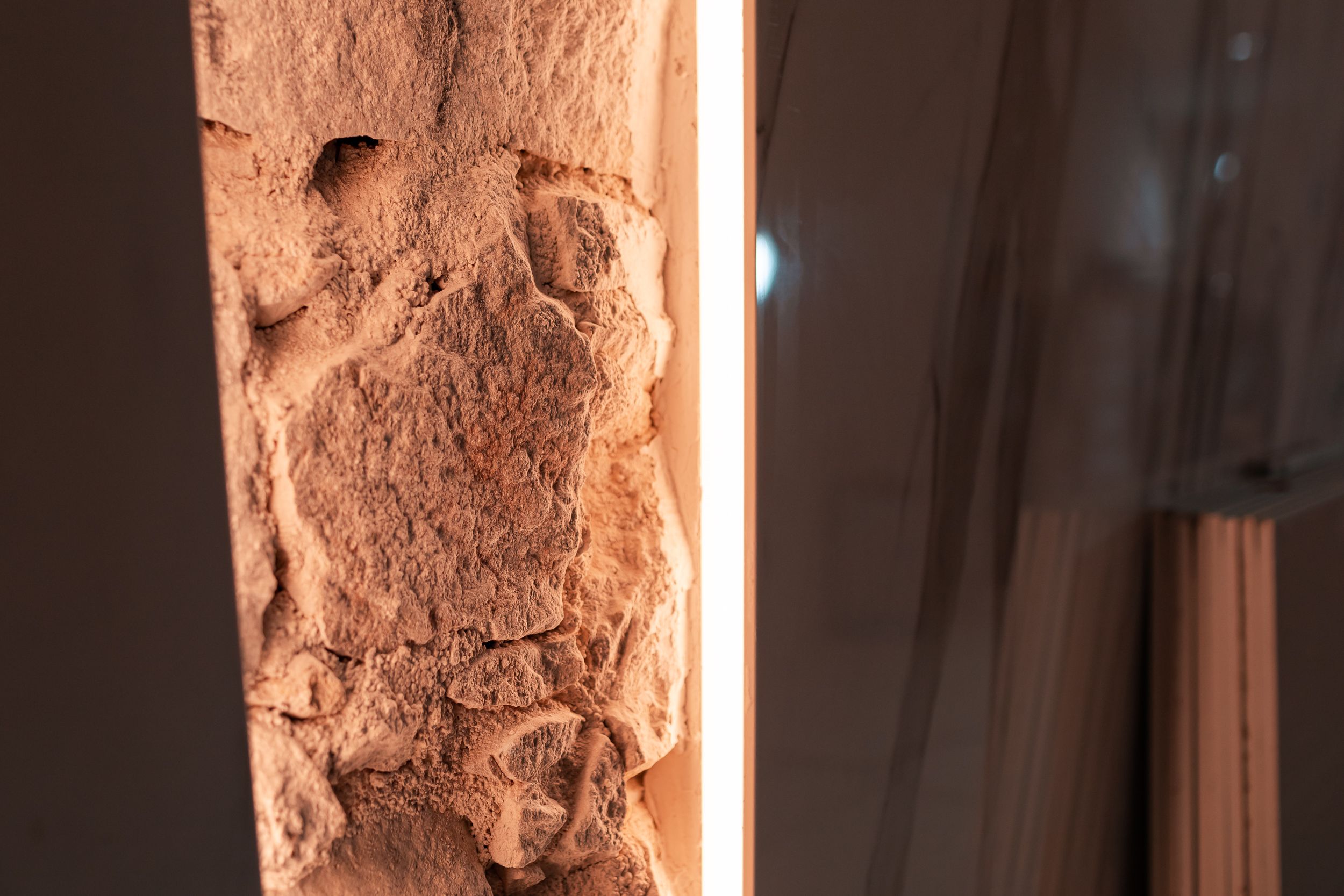 Custom lighting installed against the original 19th-century stone wall